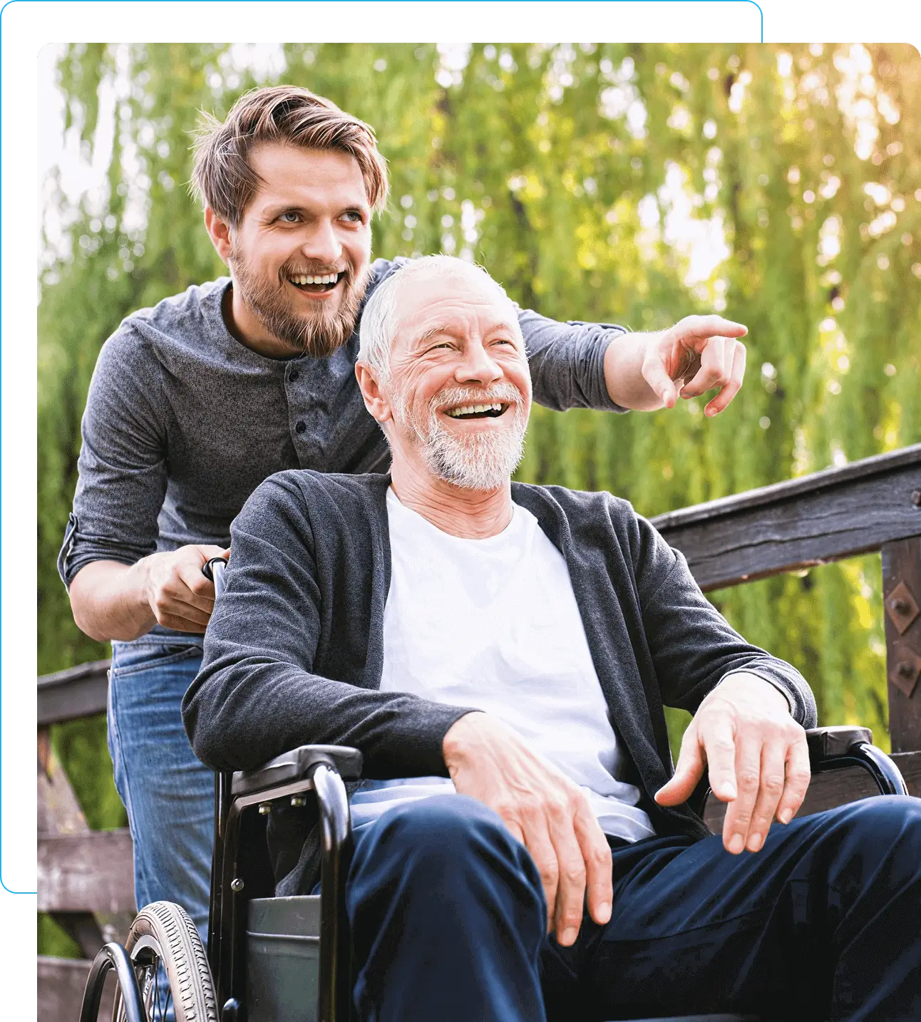 Man pushing elderly man in wheelchair, smiling.